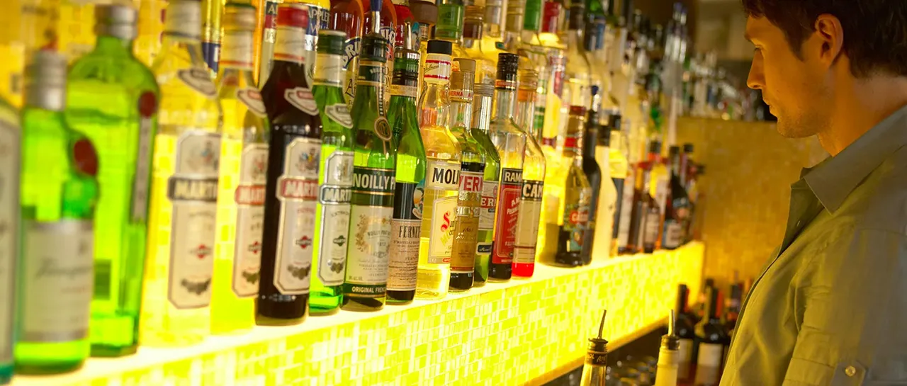 Male bartender looking at liquor shelf