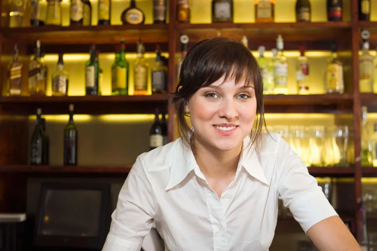 Female bartender standing in front of a liquor shelf