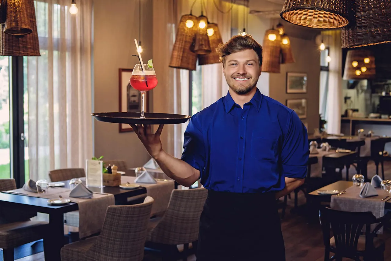 Male bartender with a cocktail on a tray