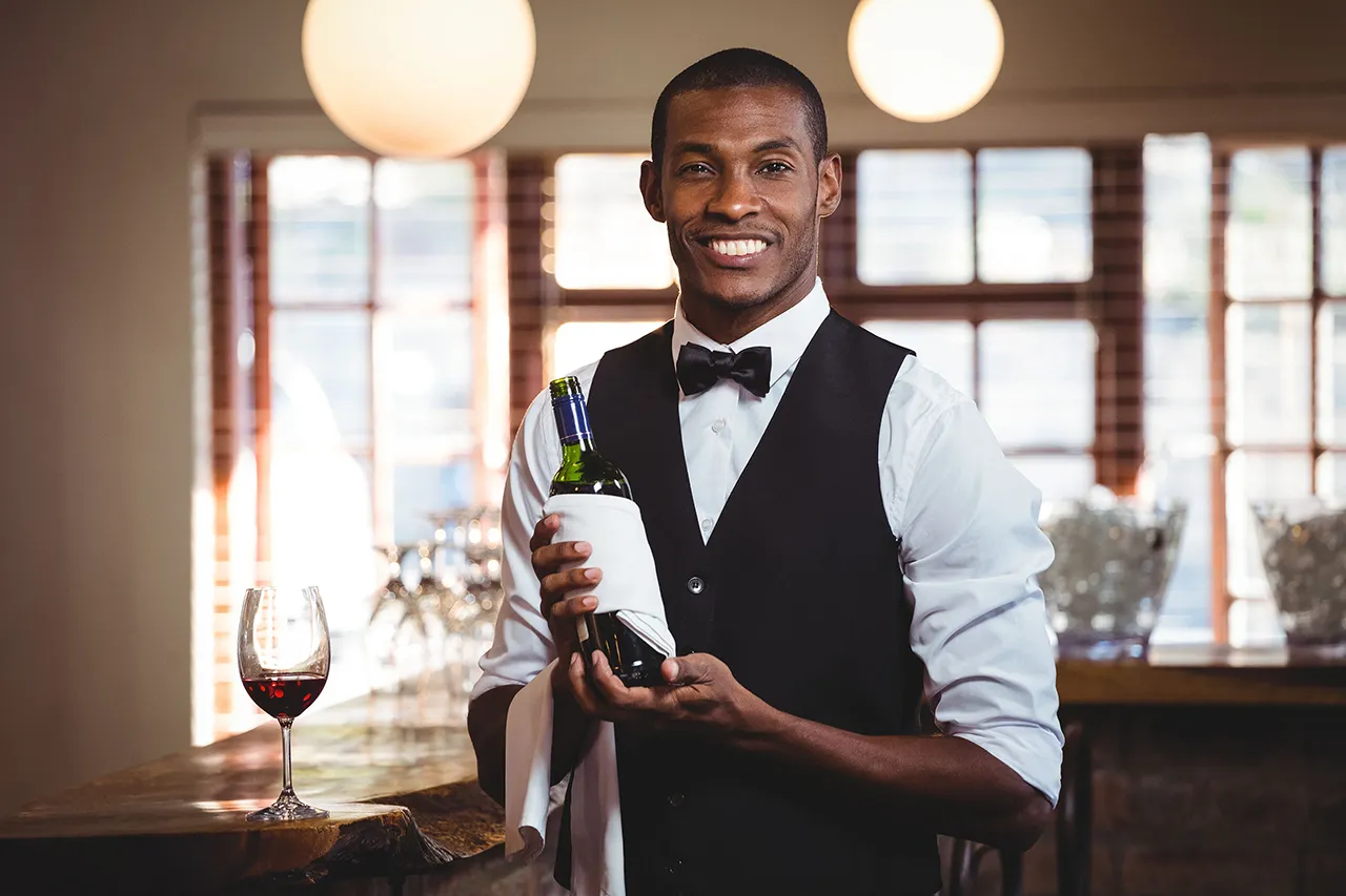 Male African American bartender with a bottle of red wine