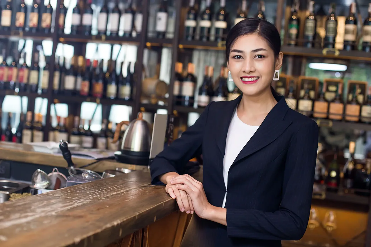 Female Asian bartender behind bar