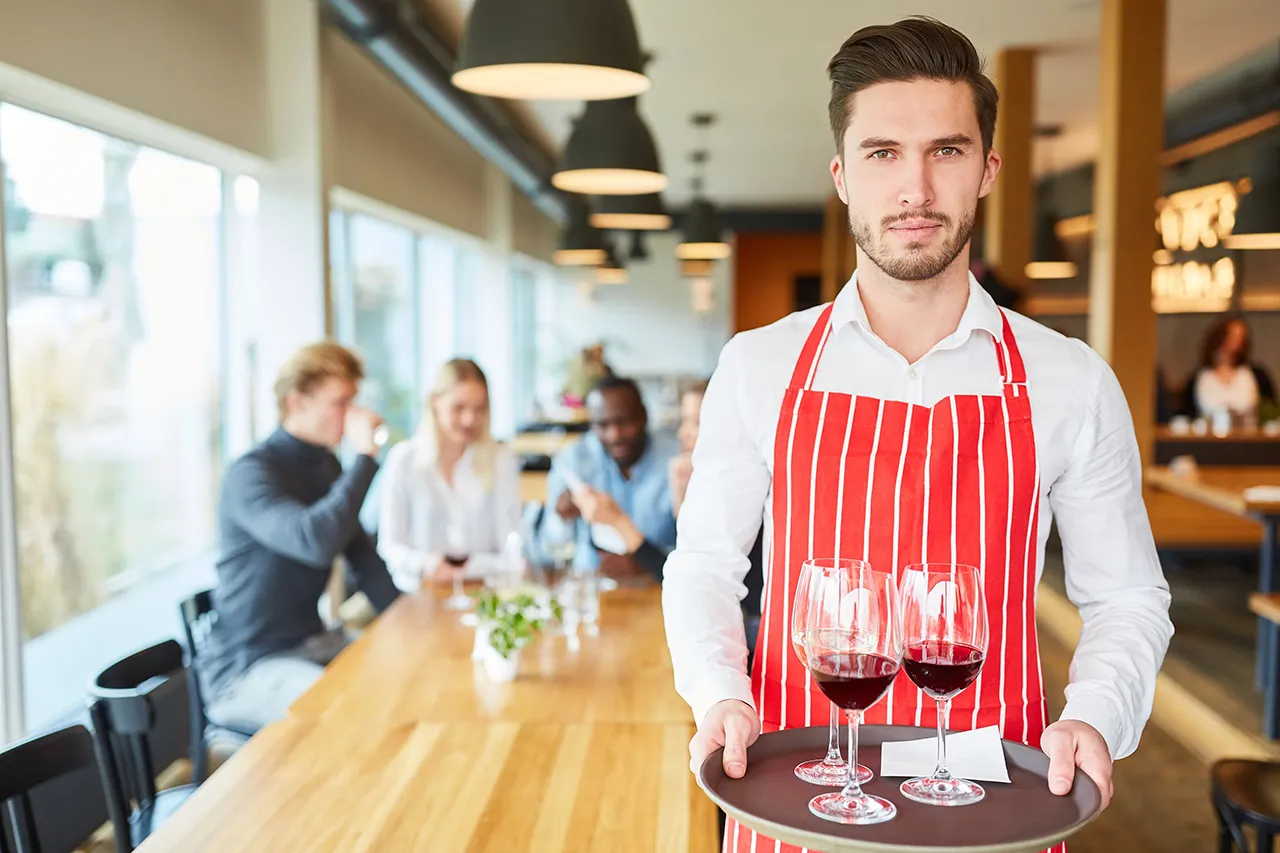 Male alcohol server with wine glasses on a tray