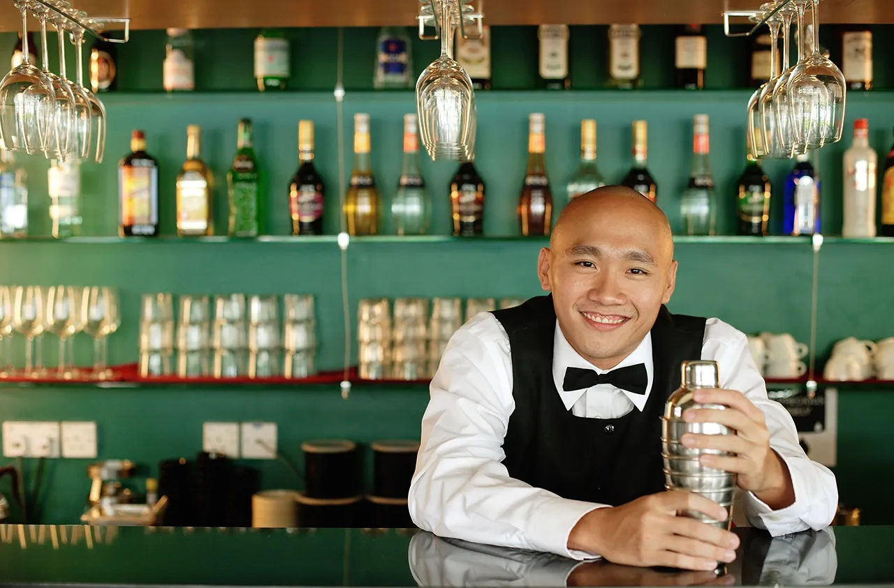 Male Asian bartender with shaker bottle